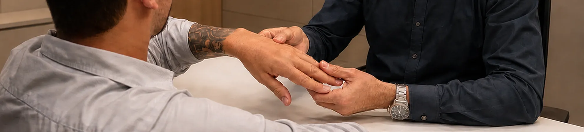 Médico examinando a mão e o punho de um paciente durante a avaliação